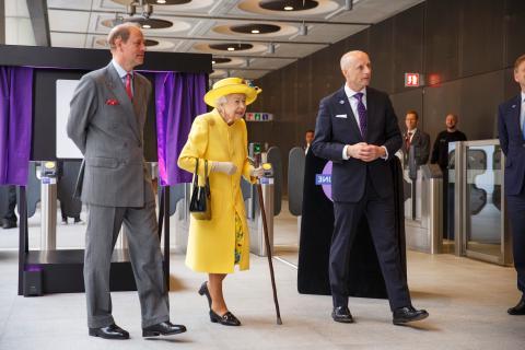 女王陛下身穿黄色外套，头戴帽子，与伦敦交通局局长安迪·拜福德和爱德华王子在一起, 左边是威塞克斯伯爵